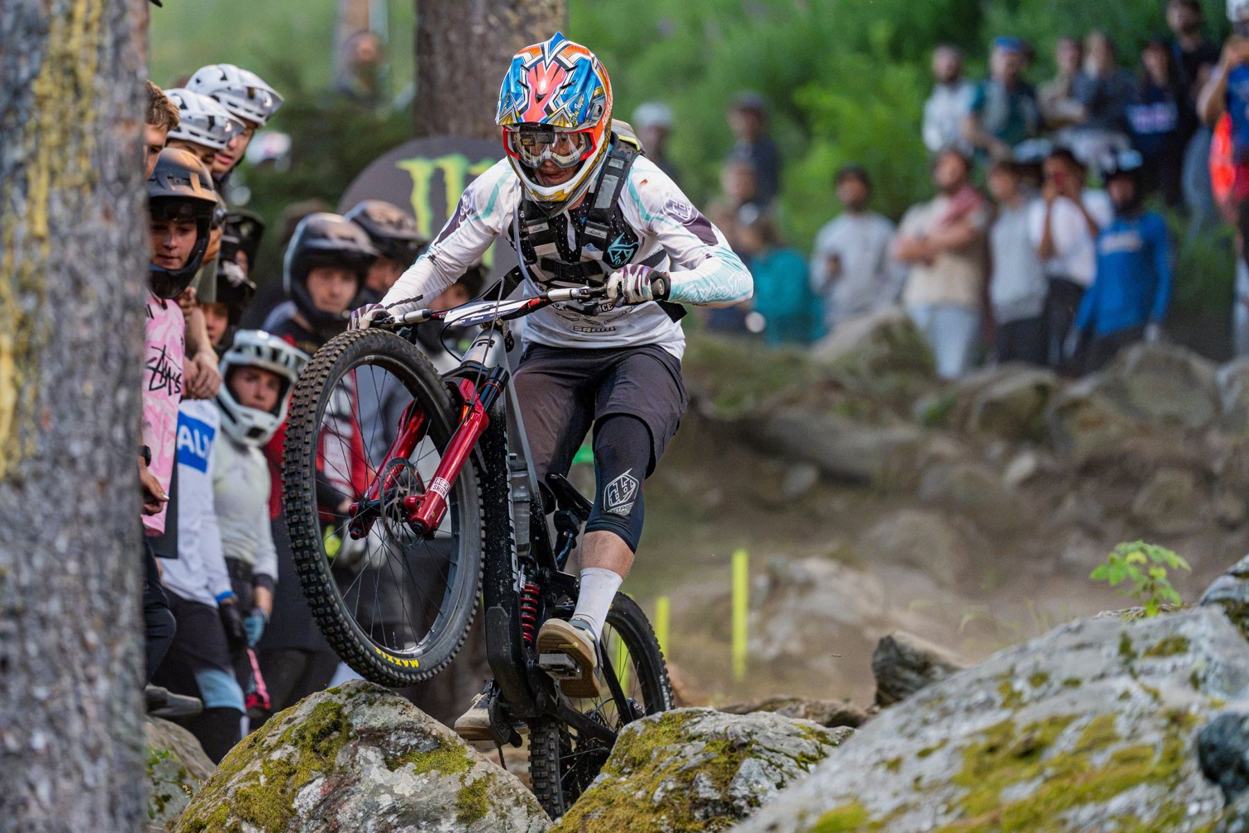 Harper riding up and over a mossy rock garden in front of a crowd
